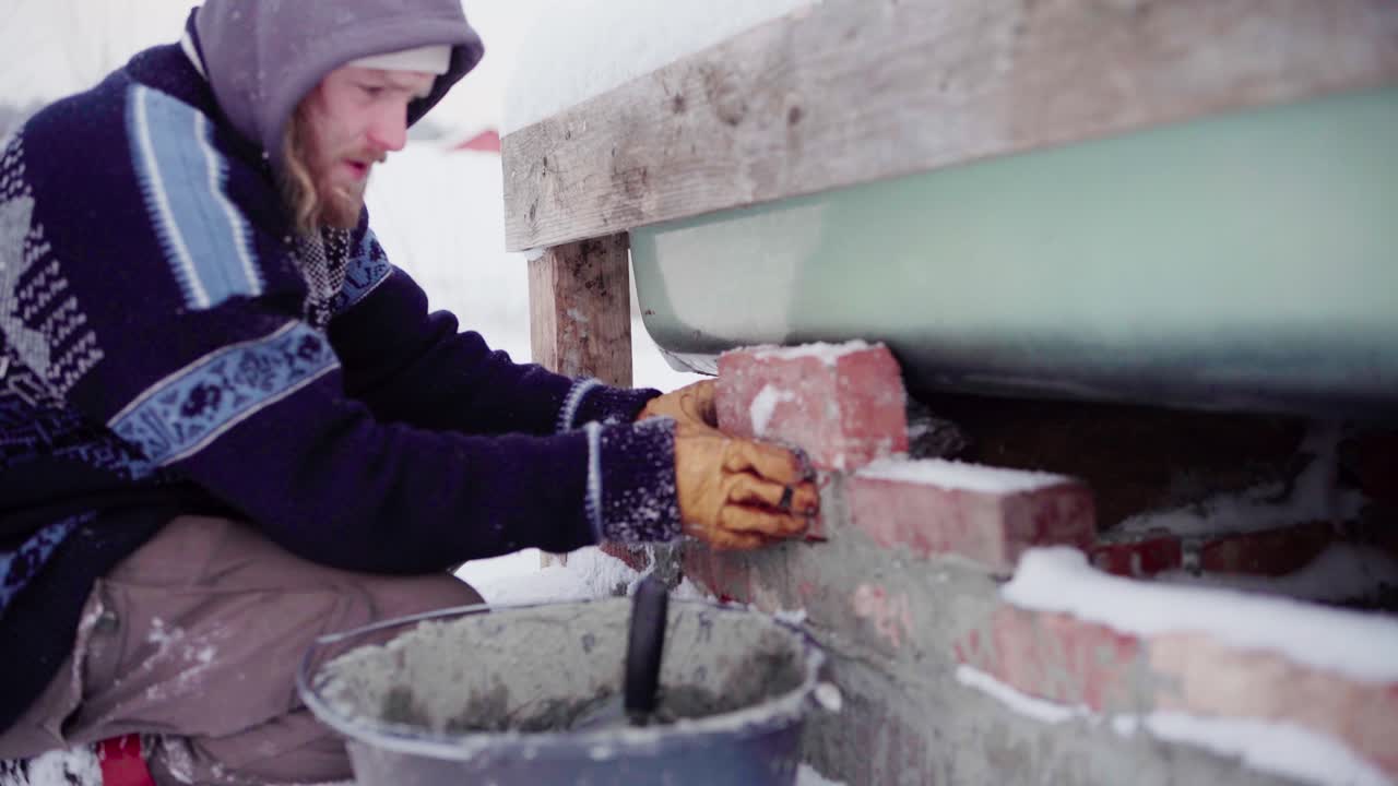 The Man is Double-checking that the Bricks Fit Before Cementing them Beneath the DIY Hot Tub - Close Up