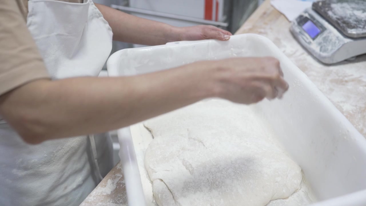 A woman rolling dough in a private bakery, captured in 4K resolution at 60fps, slow motion.