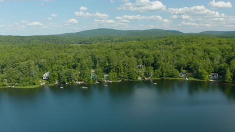 aerial drone forward moving shot over lush green thick vegetation along the shore of sunset lake in new hampshire, usa on a bright sunny day