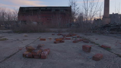 red bricks litter the ground in front of abandoned industrial buildings