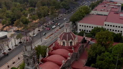 Erhöhter-Blick-Auf-Kirche-Mit-Roter-Kuppel-Und-öffentlichem-Stadtpark-Alameda-Central.-Drohnenkamera,-Die-über-Gebäude-In-Der-Innenstadt-Fliegt.-Mexiko-Stadt,-Mexiko.