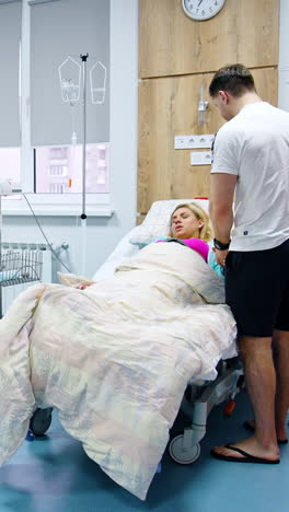woman feeling painful contractions lies in the hospital bed. man standing beside comforts her stroking her head. vertical video