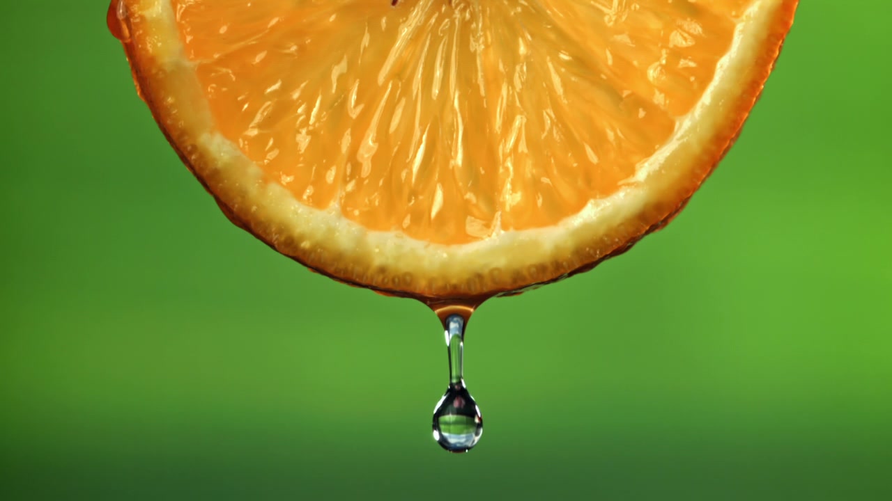 Wassertropfen fallen in Zeitlupe von einer saftigen Orangenscheibe