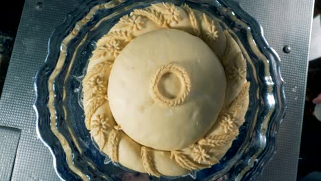 an unbaked round bread during decoration in a close view.