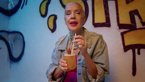 Elderly woman rest club holding cocktail at night. Happy senior moving to rhythm