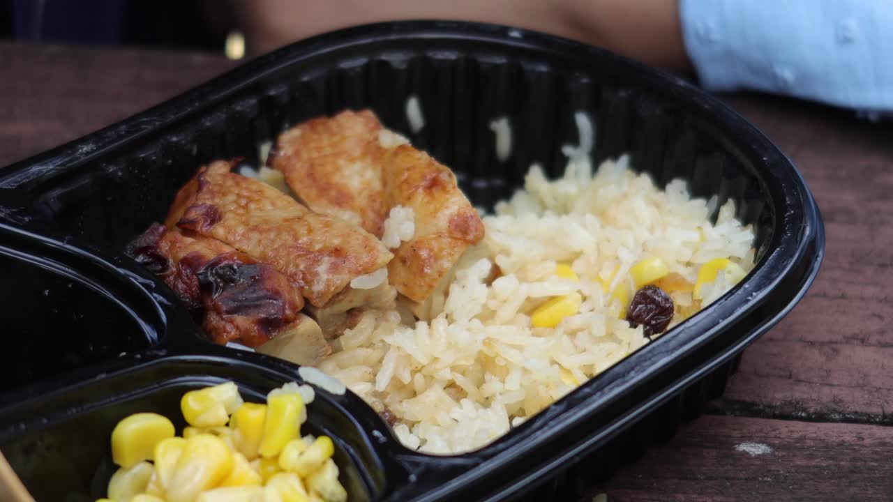Pollo al curry e riso in un pacchetto di plastica da asporto sul tavolo