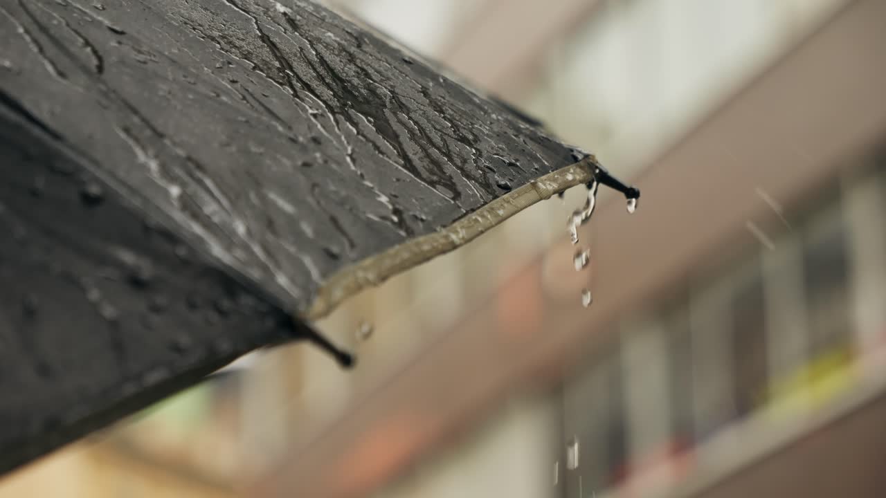 Business man tourist person with umbrella and raincoat on rainy european city street, lights reflecting, walking in Barcelona or Amsterdam during the rain