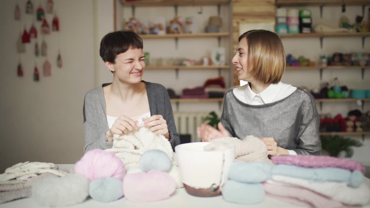 Due amiche si divertono a lavorare a maglia con filato di lana in uno studio di lavoro. Hobby femminile.