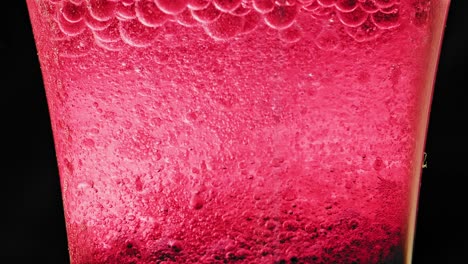 macro shot of a glass with many red bubbles floating and dripping in water