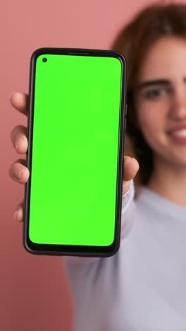 woman showing cellphone with green screen in studio. vertical footage