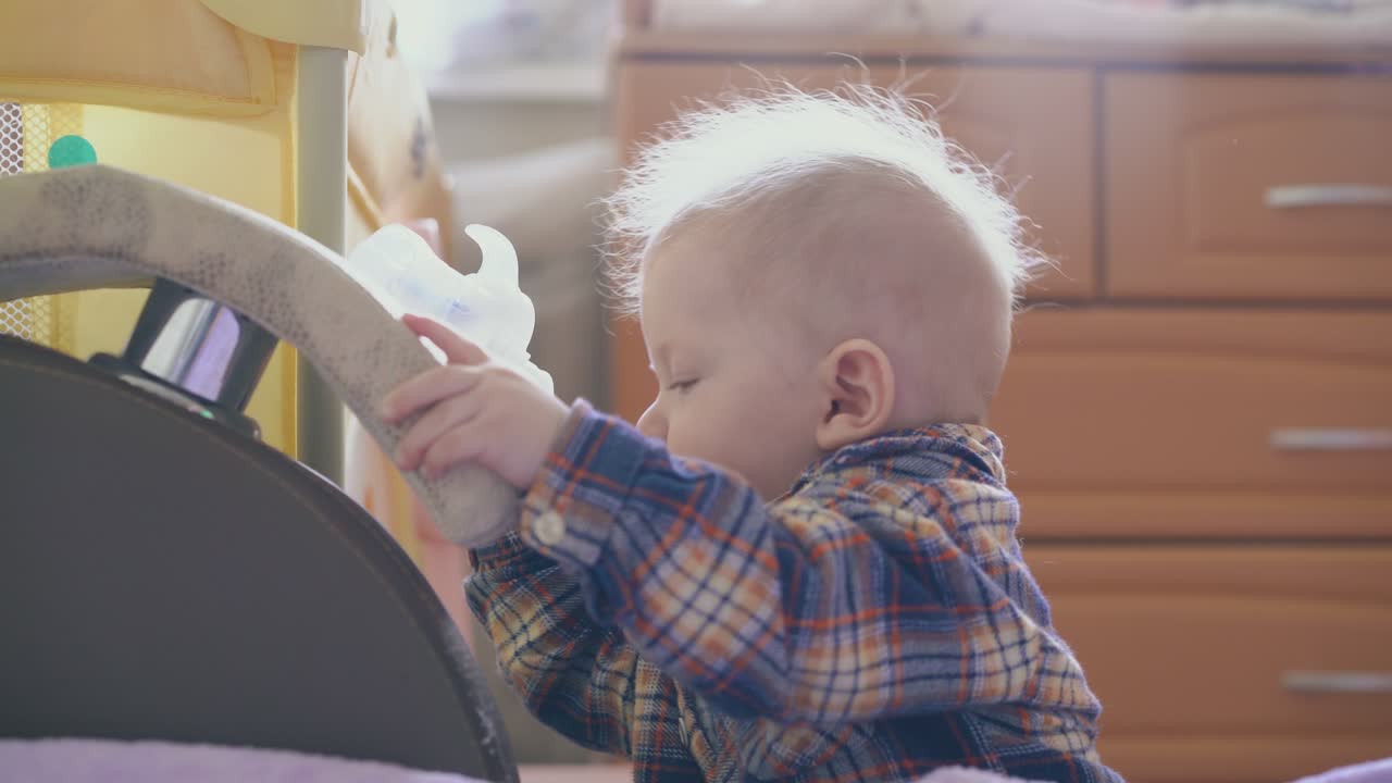 흡입기의 일부를 가진 귀여운 소년은 큰 부드러운 침대에 서 있습니다