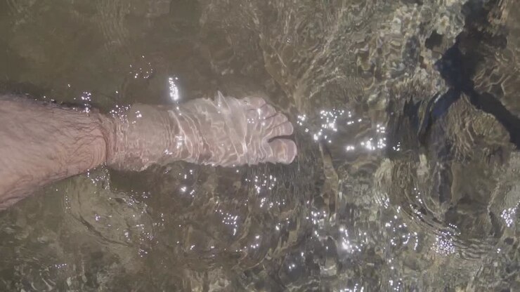 A man's foot in the water at the beach on vacation giving a sense of freedom and relaxation