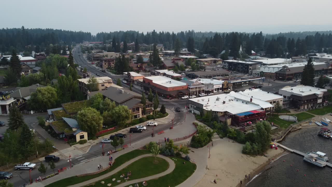 toma de drones en sentido contrario a las agujas del reloj de automóviles que ingresan a la ciudad junto al lago de mccall, idaho durante la puesta de sol