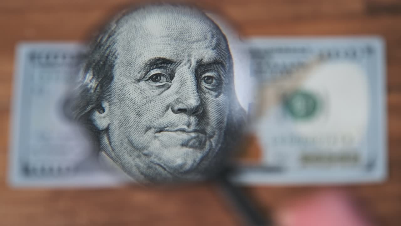 cien dólares inspecciona bajo lupa en una mesa de madera