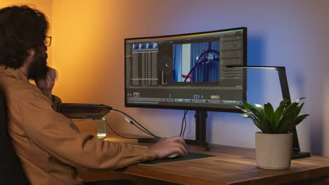 side portrait shot of a young man on nice desk setup editing video project, time lapse