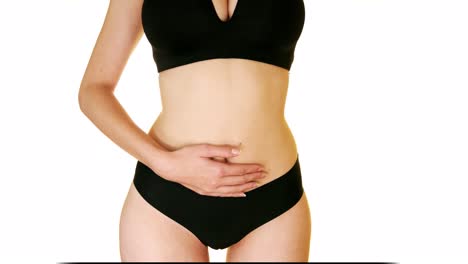 one armed woman carefully touches her stomach on a white background, close up studio shot