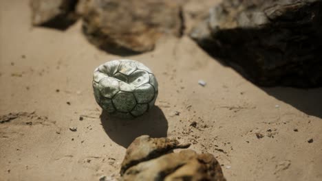 vieja pelota de fútbol en la playa de arena