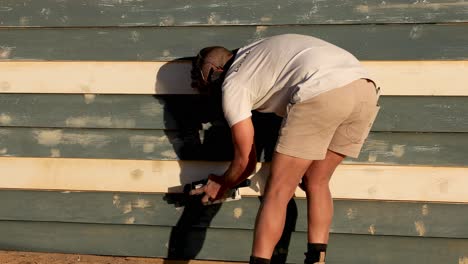 man fixing wooden wall at brighton beach