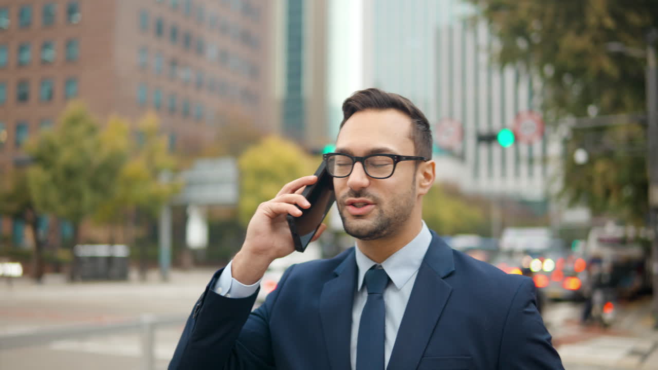 hombre de negocios caminando por la acera de la ciudad, hablando por teléfono