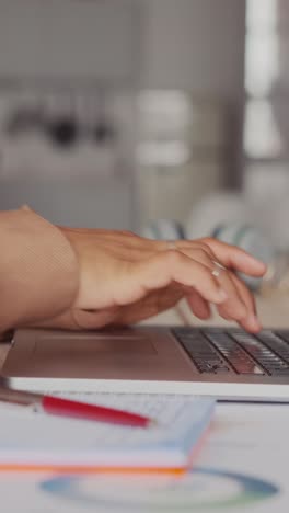 young african american woman typing text on laptop and taking notes in notepad