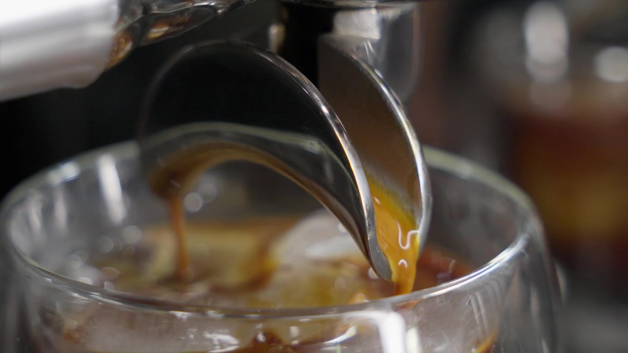 Macchina da caffè espresso che estrae il caffè che scorre nel bicchiere, primo piano