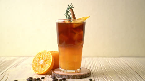 A-glass-of-iced-americano-black-coffee-and-layer-of-orange-and-lemon-juice-decorated-with-rosemary-and-cinnamon