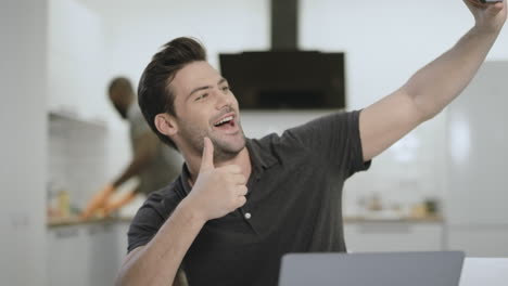 hombre guapo tomando una selfie en la cocina abierta. joven haciendo el gesto de v.