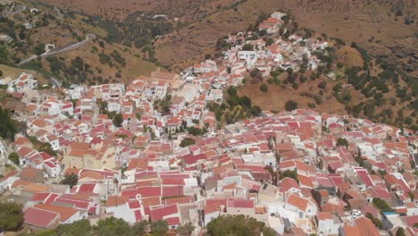 Vuelo-Aéreo-Hacia-Atrás-Por-Encima-De-La-Ciudad-De-Ioulida-En-Kea-Con-Cultivos-Paisajísticos