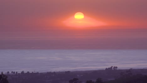 Lapso-De-Tiempo-De-Una-Enorme-Bola-Redonda-Roja-De-Puesta-De-Sol-Al-Atardecer-Sobre-El-Océano-Pacífico-Cerca-De-Malibu,-California