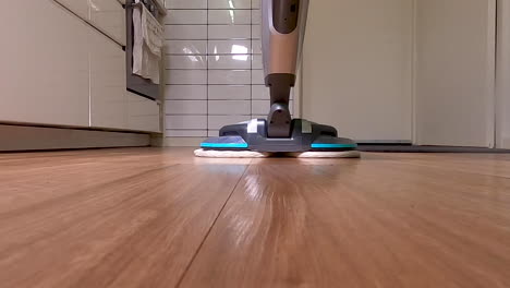 cleaning the kitchen floorboards with a floor polisher