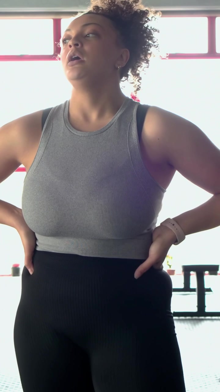 Video verticale: Donna con canotta grigia usa le battle ropes facendo onde in palestra, controlla l'orologio per il polso.