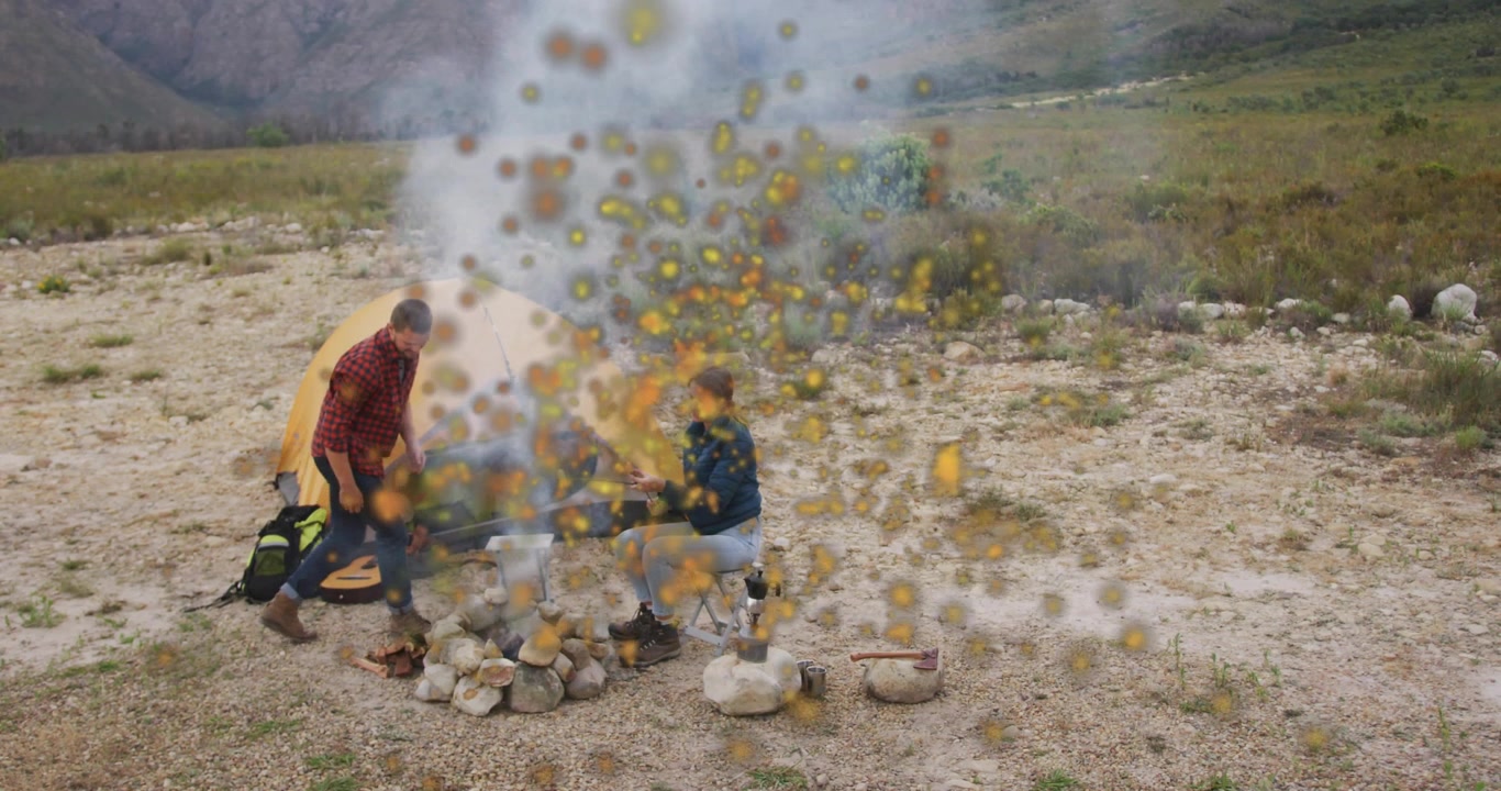 Una coppia arriva a un campeggio in montagna, monta la tenda e alimenta il fuoco con scintille che turbinano per cucinare.