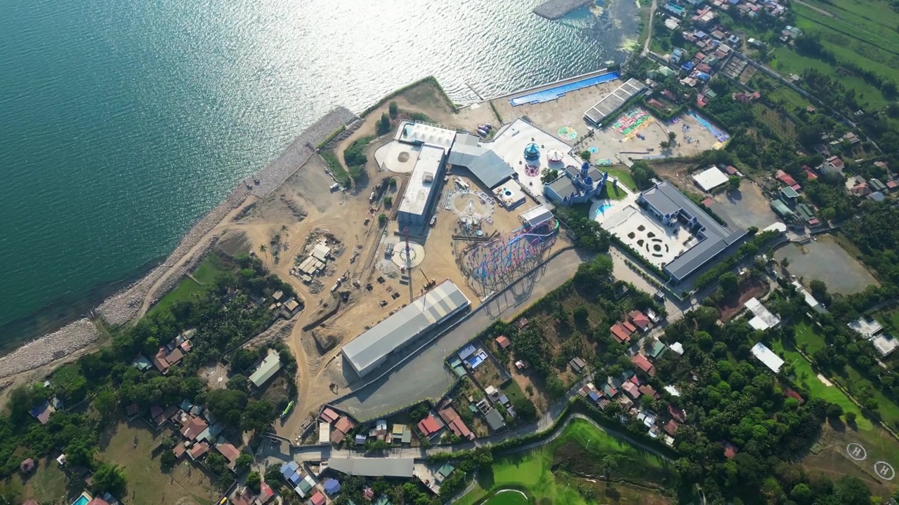 Panorama aéreo que muestra edificios de resorts junto a las tranquilas aguas del Lago Taal y vegetación tropical en Taunan, Batangas, Filipinas.