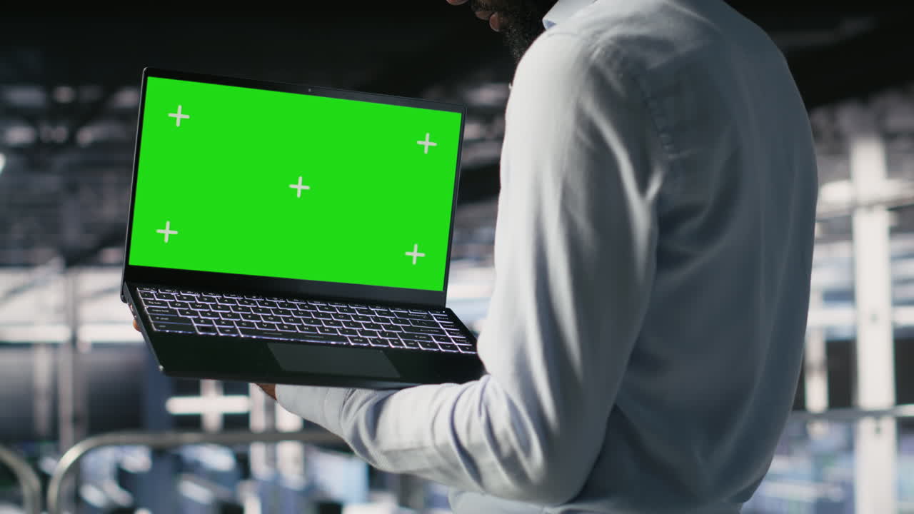 Technicians in data center analyzing performance outputs on green screen laptop