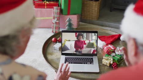 Pareja-Caucásica-Mayor-Usando-Una-Computadora-Portátil-Para-Una-Videollamada-Navideña-Con-Una-Mujer-Feliz-En-La-Pantalla