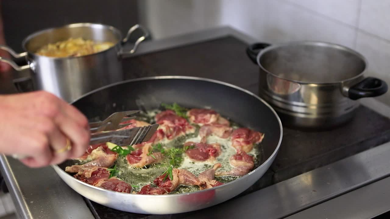 el chef de cocina profesional cocina carne en una sartén en una cocina comercial en un restaurante