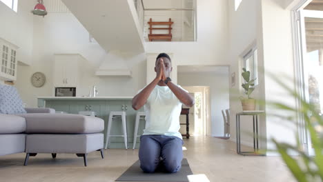 Focused-african-american-man-practising-yoga-meditation-in-sunny-living-room,-slow-motion