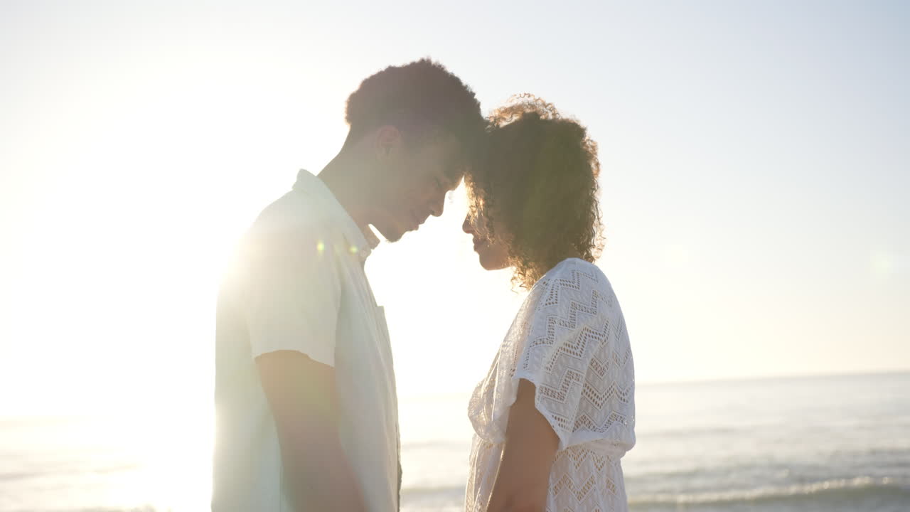 Biracial couple shares a tender moment on the beach at sunset