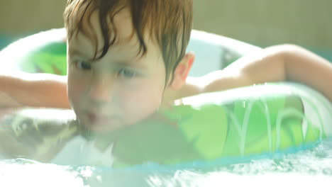 Lindo-Niño-Divirtiéndose-Nadando-Con-Anillo-De-Goma-En-La-Piscina