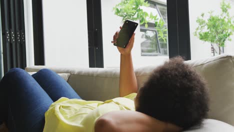 Video-of-plus-size-african-american-woman-relaxing-on-sofa-with-smartphone