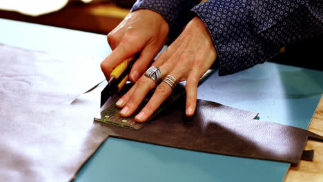 mid-section of craftswoman cutting leather