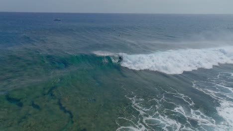 Surfer-Surft-Auf-Einer-Welle-Im-Seichten-Wasser,-Gefilmt-Mit-Einer-Drohne,-Hermitage-Beach-Auf-Der-Insel-Réunion