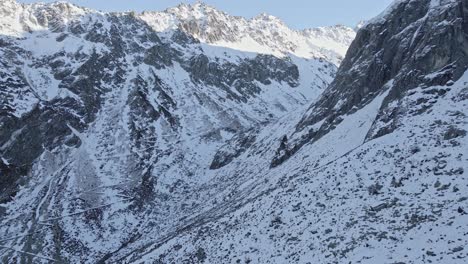 imágenes de drones de montañas nevadas con un pequeño camino en la ladera de la montaña