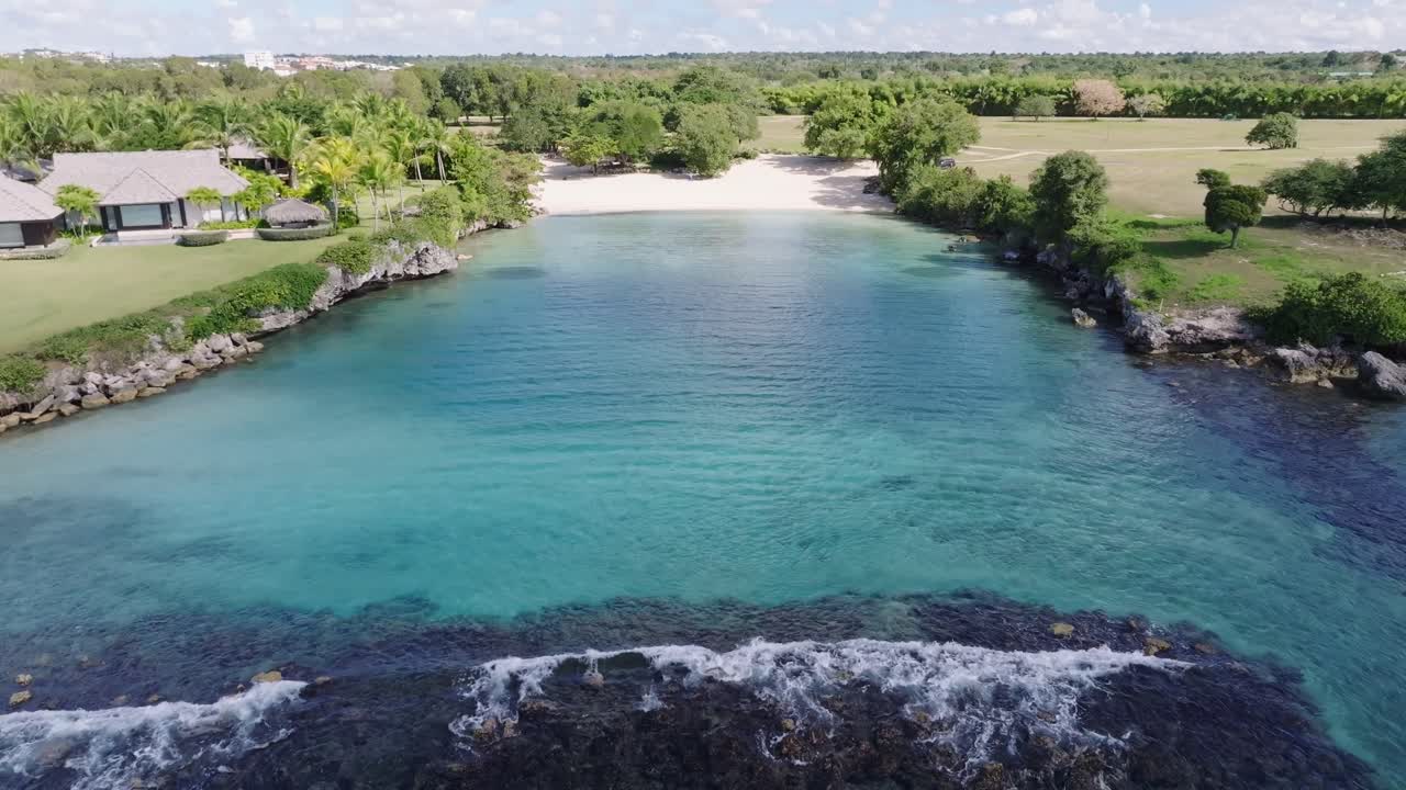 Smooth dolly-in aerial over Caleton Beach, Dominican Republic, showcasing turquoise bay and coral reef
