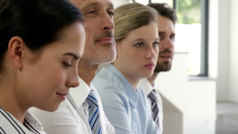 business people seated in a meeting and taking notes