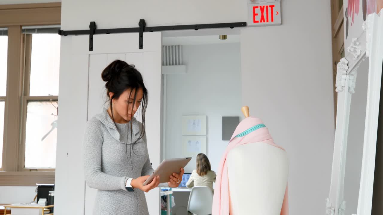 패션 디자이너가 태블릿을 사용하여 드레스 메이커 모델 4k의 직물을 검사합니다.