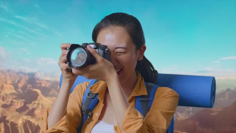 close up of asian female hiker with mountaineering backpack using a camera taking picture while traveling at the top of mountain