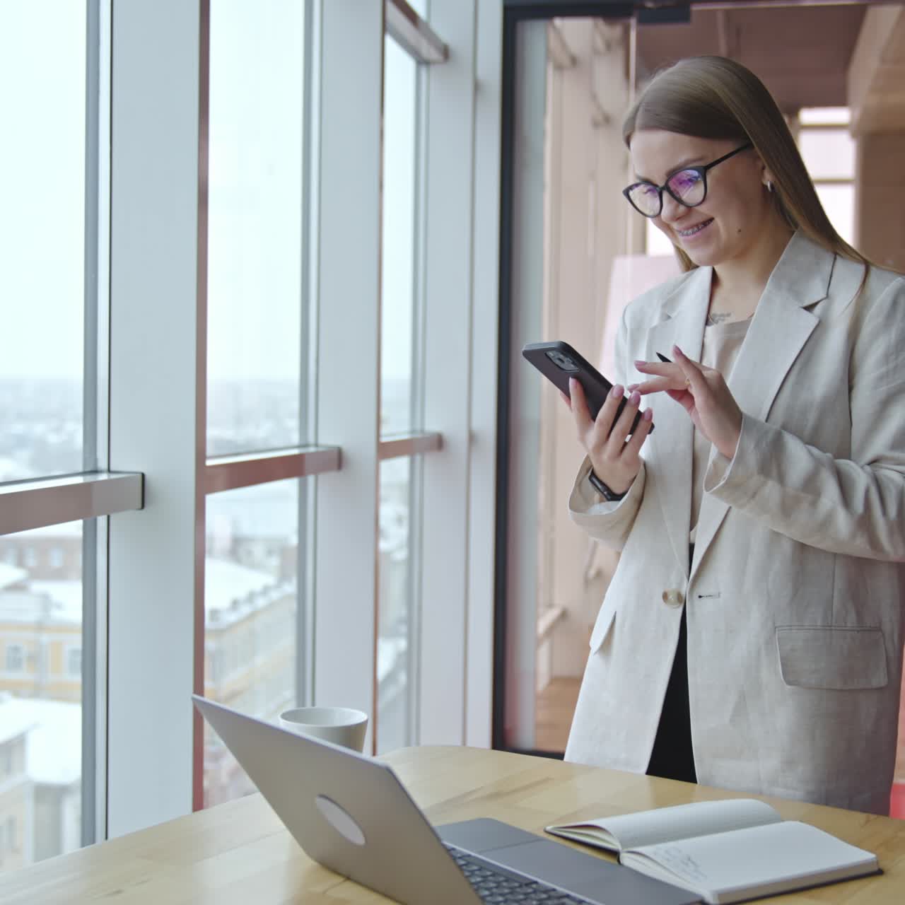 Business lady standing near the window with phone. Office female worker have a phone call