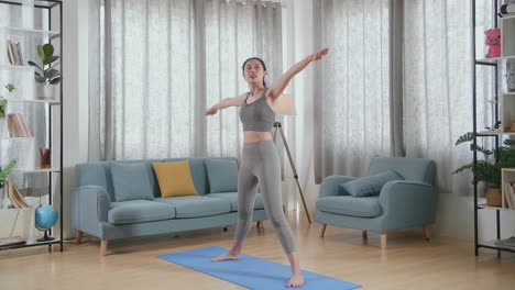 joven atleta asiática con ropa deportiva estirándose y practicando yoga en casa. estilo de vida saludable, fitness, bienestar y concepto de atención plena