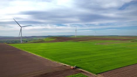 wind turbines and tractor working on land at sunset in ruginoasa iasi romania